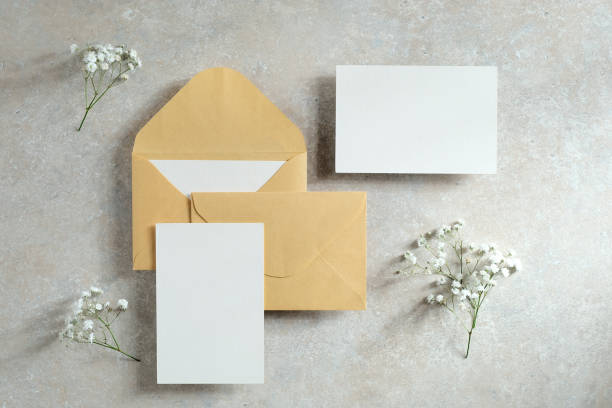 istock Blank paper cards, envelopes, flowers on concrete table. Wedding invitations mockups. Flat lay, top view. 1296216578