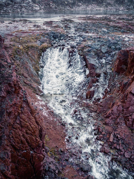 Frozen waterfall from a cliff. Atmospheric minimalist Arctic landscape with a hanging glacier on a rocky mountain top.