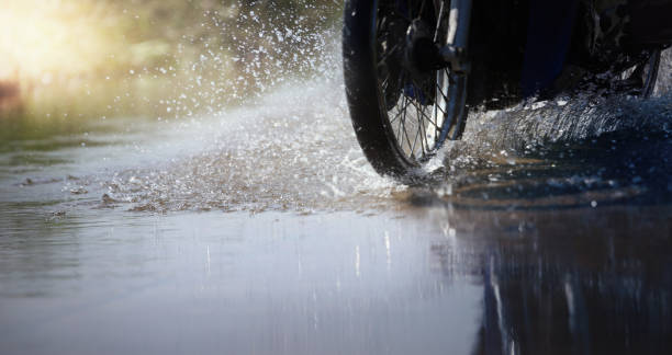 Motorcycle run through flood water after hard rain with water spray from the wheels. stock photo