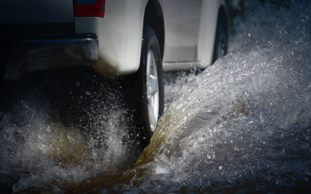 voiture courir à travers l’eau d’inondation après la pluie dure avec le jet d’eau des roues. - safe ride photos et images de collection
