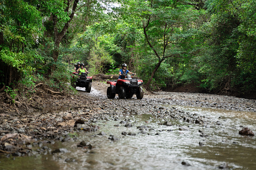 Group of tourists driving 4x4 bikes vehicles thru a creek in Central America