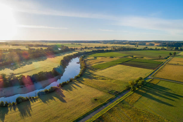 istock Snowy River and fields at sunset with lens flare - aerial view 1296241982