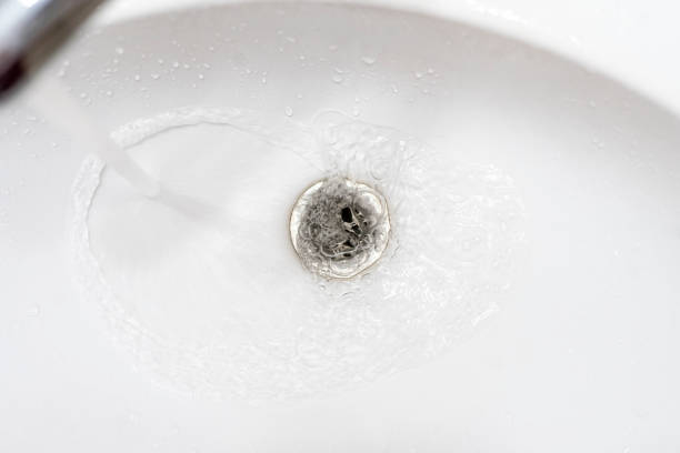 istock water draining from sink, pouring liquid in the hole 1296253765