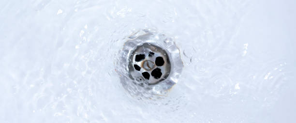 istock water draining from sink, pouring liquid in the hole 1296253769