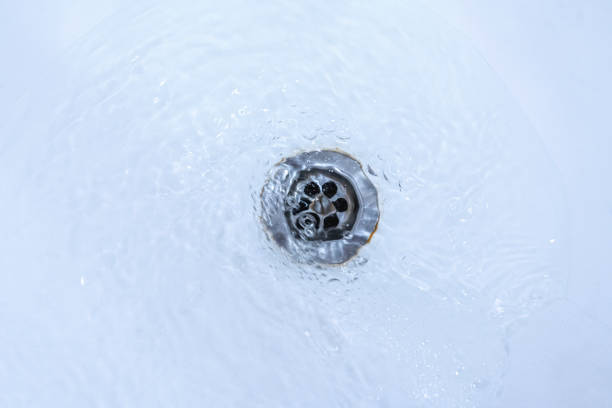 istock water draining from sink, pouring liquid in the hole 1296253788