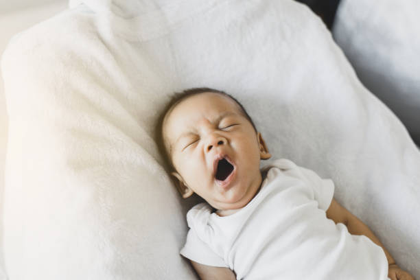 bébé nouveau-né paresseux bâillant avant sommeil sur un lit confortable à la maison - baby yawning asian ethnicity newborn photos et images de collection