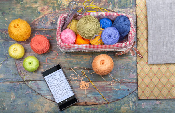 A crochet set and a smartphone are layout on a shabby wooden table