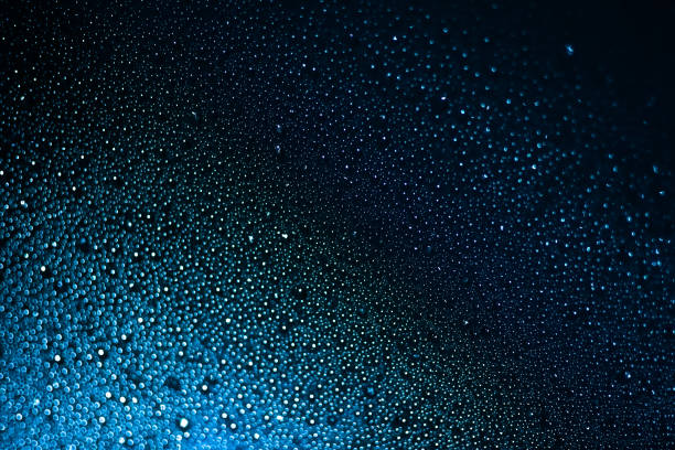 istock Raindrops on blue glass background close-up. Water drops blue texture 1296261240