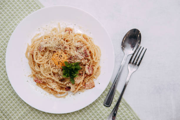 spaghetti carbonara sur une plaque blanche sur la table. aliments faits maison - lard close up pasta eggs photos et images de collection