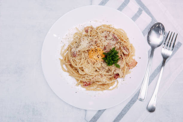 spaghetti carbonara sur une plaque blanche sur la table. aliments faits maison - lard close up pasta eggs photos et images de collection