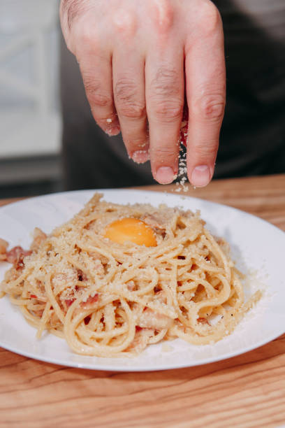 spaghetti carbonara sur une plaque blanche sur la table. aliments faits maison - lard close up pasta eggs photos et images de collection