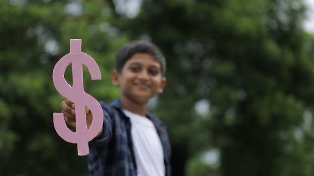 Cute indian little child holding dollar Sign on nature Background