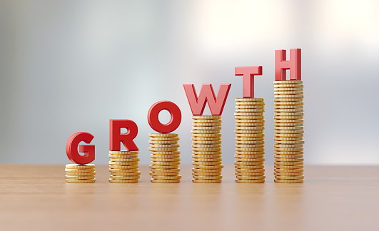 Red letters sitting over coin stacks write growth before defocused background. Horizontal composition with copy space. Great use for financial growth concepts.