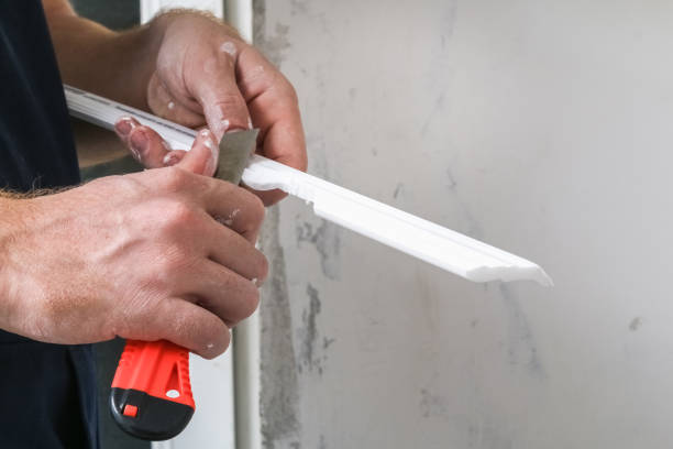 istock Worker fixes the plastic molding to ceiling. Installation of ceiling cornice. 1296266542