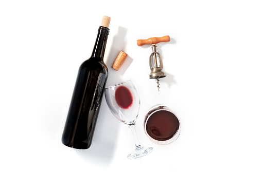 Wine tasting, overhead flat lay shot on a white background, with a cork, a vintage corkscrew, a bottle and two glasses