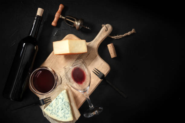 istock Wine and cheese tasting, overhead shot on a black background, with a vintage corkscrew and a bottle 1296268011