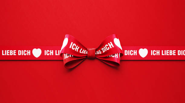 istock I Love You ( Ich Liebe Dich in German ) Written Red Ribbon over Red Background 1296268065