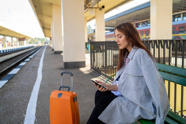 istock Young woman waiting on station and using smart phone 1296268380