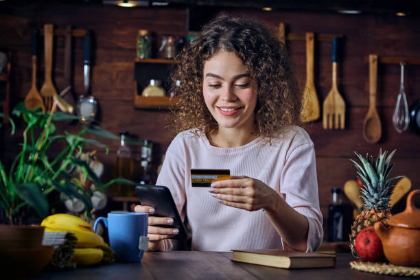 istock Hispanic curly hair Young woman shopping online using smart phone in a rustic kitchen 1296268433
