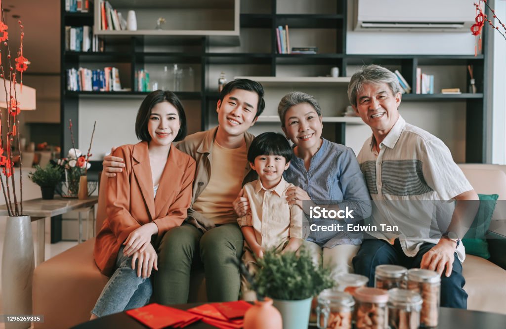 Chinesische neue Jahr Mehrgenerationenfamilie sitzt auf Sofa Wohnzimmer Blick auf die Kamera lächelnd glücklich - Lizenzfrei Ostasiatische Kultur Stock-Foto