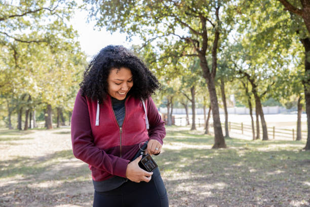 mujer joven revisa la bomba de insulina y el monitor de azúcar en la sangre mientras camina al aire libre - diabetes fotografías e imágenes de stock