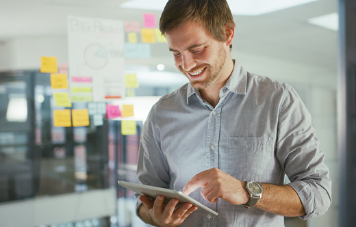 Shot of a young businessman using a digital tablet while having a brainstorming session in a modern office