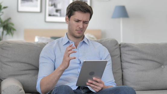Handsome Young Man in Shock by Loss while Using Tablet