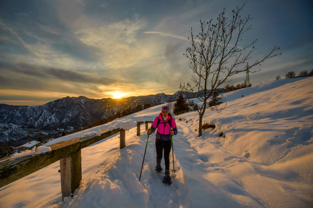 jovem sozinha em caminhada snowshoe em belo dia do pôr do sol - snowshoeing snowshoe women shoe - fotografias e filmes do acervo