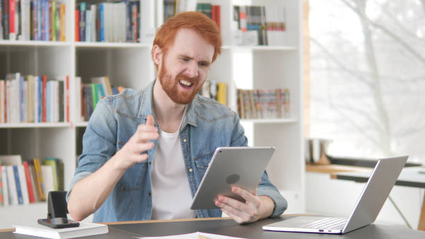 istock Upset Young Casual Redhead Man Facing Loss on Tablet 1296274815