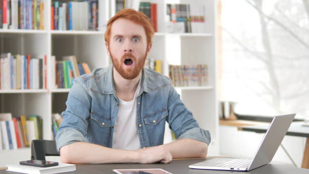 istock Young Casual Redhead Man in Shock Looking at Camera 1296274842