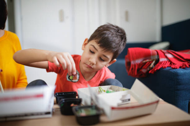 niño sentado en el suelo junto a su madre y mojando rollo de sushi en salsa - japanese cuisine soy sauce food bonito fotografías e imágenes de stock