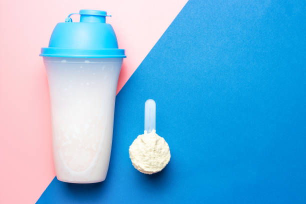 shaker and scoop with protein on pink and blue background, copy space - body building milk shake protein drink drink imagens e fotografias de stock