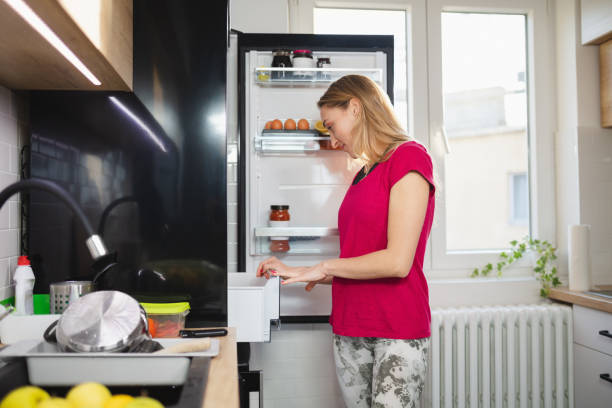 istock Fit woman standing by the open fridge and looking inside 1296275878