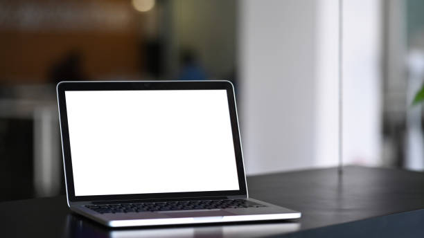 istock Mock up laptop computer with blank white screen on black wooden table at modern office. 1296276146
