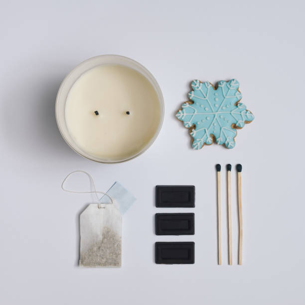 Winter composition made with chocolate, snowflake cookie, tea bag, matches and candle. Minimal flat lay on white background.