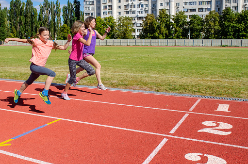 Family fitness, mother and kids running on stadium track, exercise with children  and sport healthy lifestyle concept