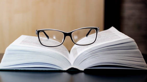istock Glasses on open book on wooden table 1296279444