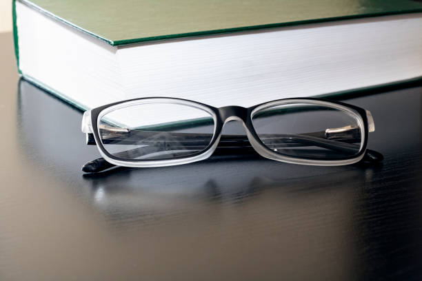istock Black glasses and a book on a wooden table 1296279467