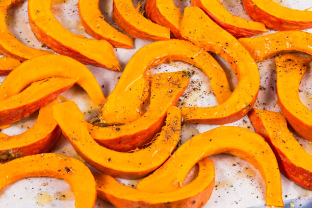 istock Pumpkin cut into small wedges for baking on a metal baking sheet, close-up 1296283647
