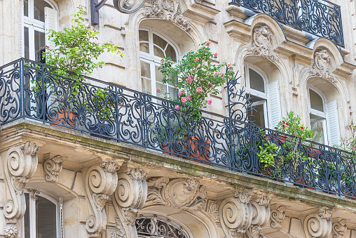Beautiful parisian building with balcony decorated by flowers