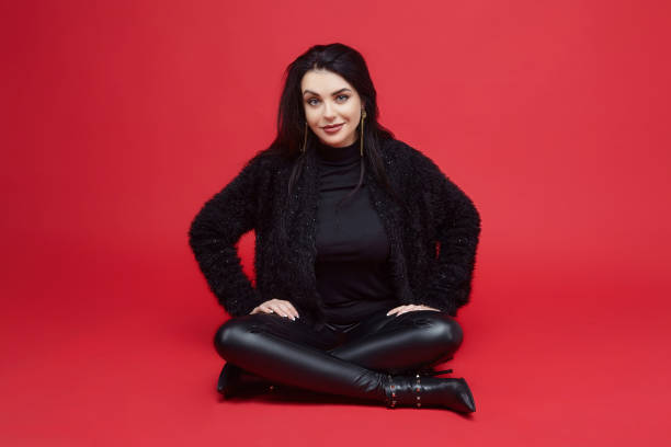 istock attractive brunette with long hair sitting in the Studio on a red background 1296284780