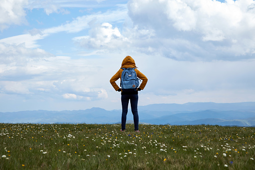 One woman on a big meadow and landscape mountain top view.