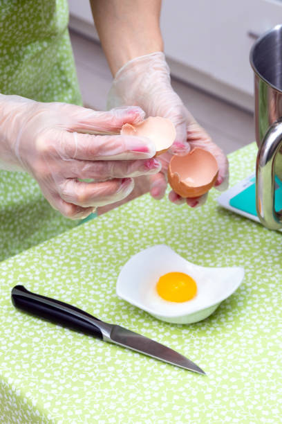 istock Women's gloved hands hold the shell after breaking the egg. Selective focus. 1296289178