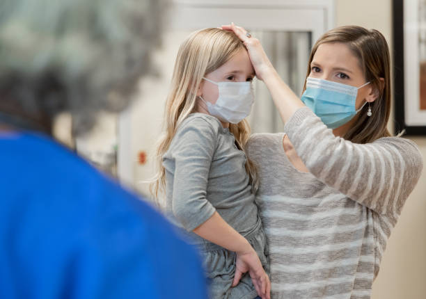 Mother explains young daughter's fever and symptoms to a pediatrician at hospital Mother explains young daughter's fever and symptoms to a pediatrician at hospital emergency room photos stock pictures, royalty-free photos & images