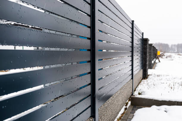istock Modern anthracite panel fencing, with a visible fence foundation connector, it rains in winter, in the background there is snow lying on the ground. 1296290716