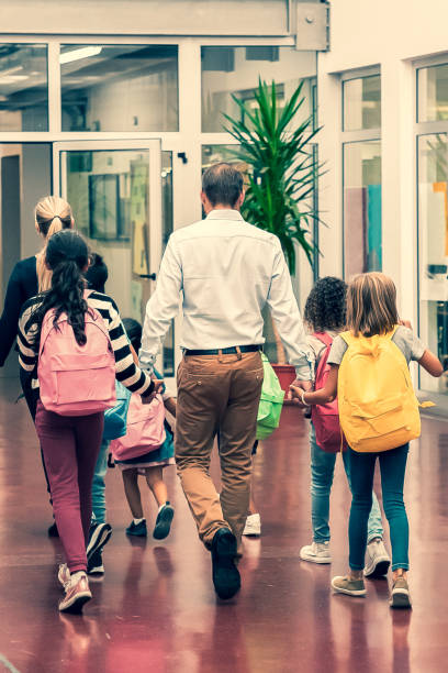 istock Schoolkids with bright backpacks walking through hallway 1296290857