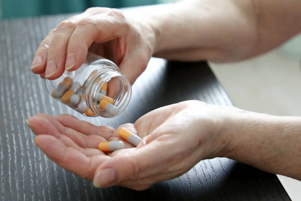 istock Elderly woman with pills in wrinkled hands 1296290892