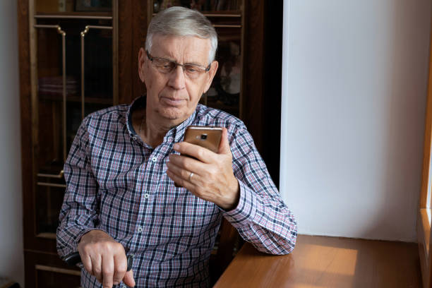 istock A satisfied old man sits at home, looks at his mobile phone, uses the Internet. 1296293657