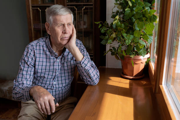 istock A lonely old man sits at home and looks thoughtfully out the window. 1296293823