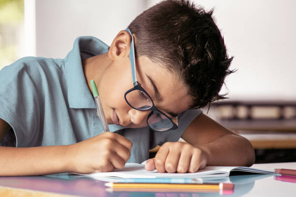 istock Focused Latin boy in glasses sitting at school desk 1296293826